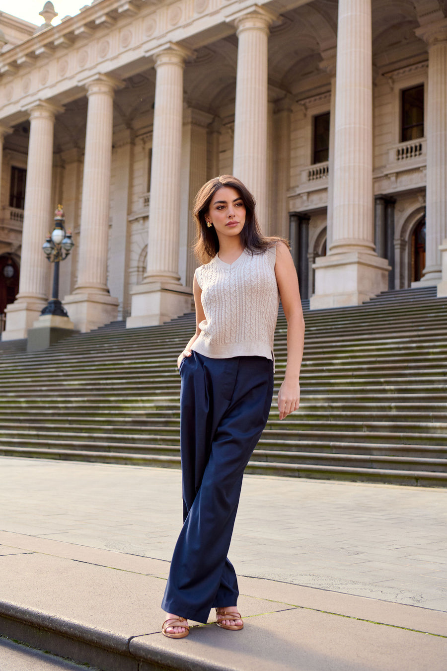 Woman wearing a petite cable knit vest and petite wool pants in navy made for shorter women