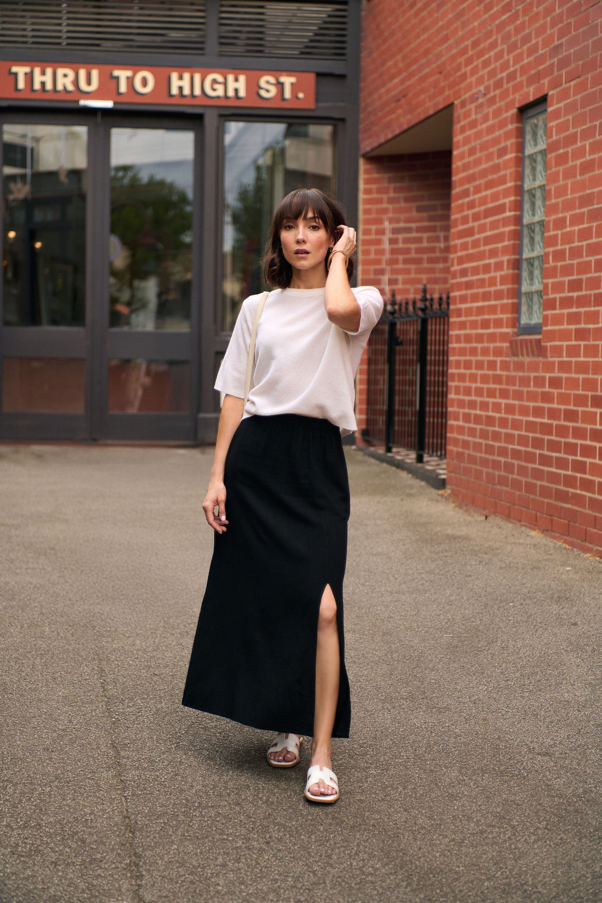 Woman wearing a black petite maxi skirt and white knit top