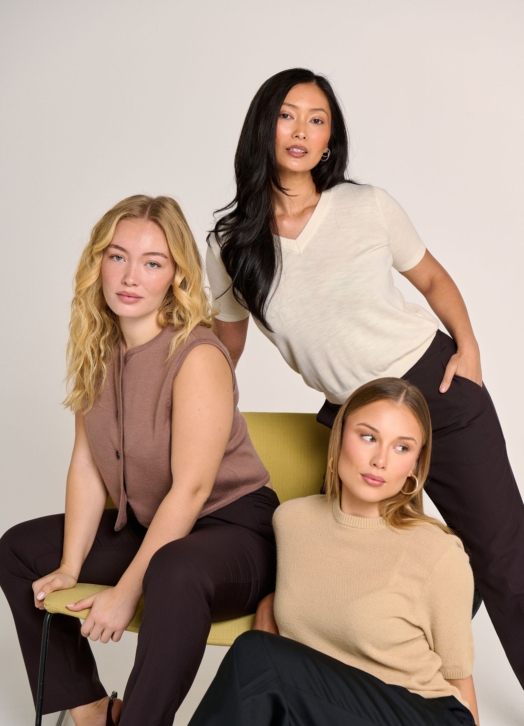 Three women posing together against a plain background