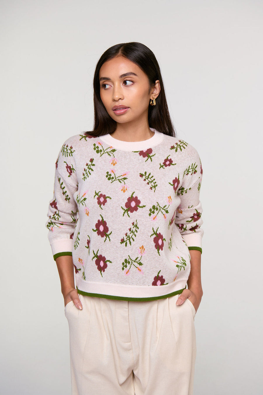 Woman wearing a petite floral-patterned sweater against a plain background