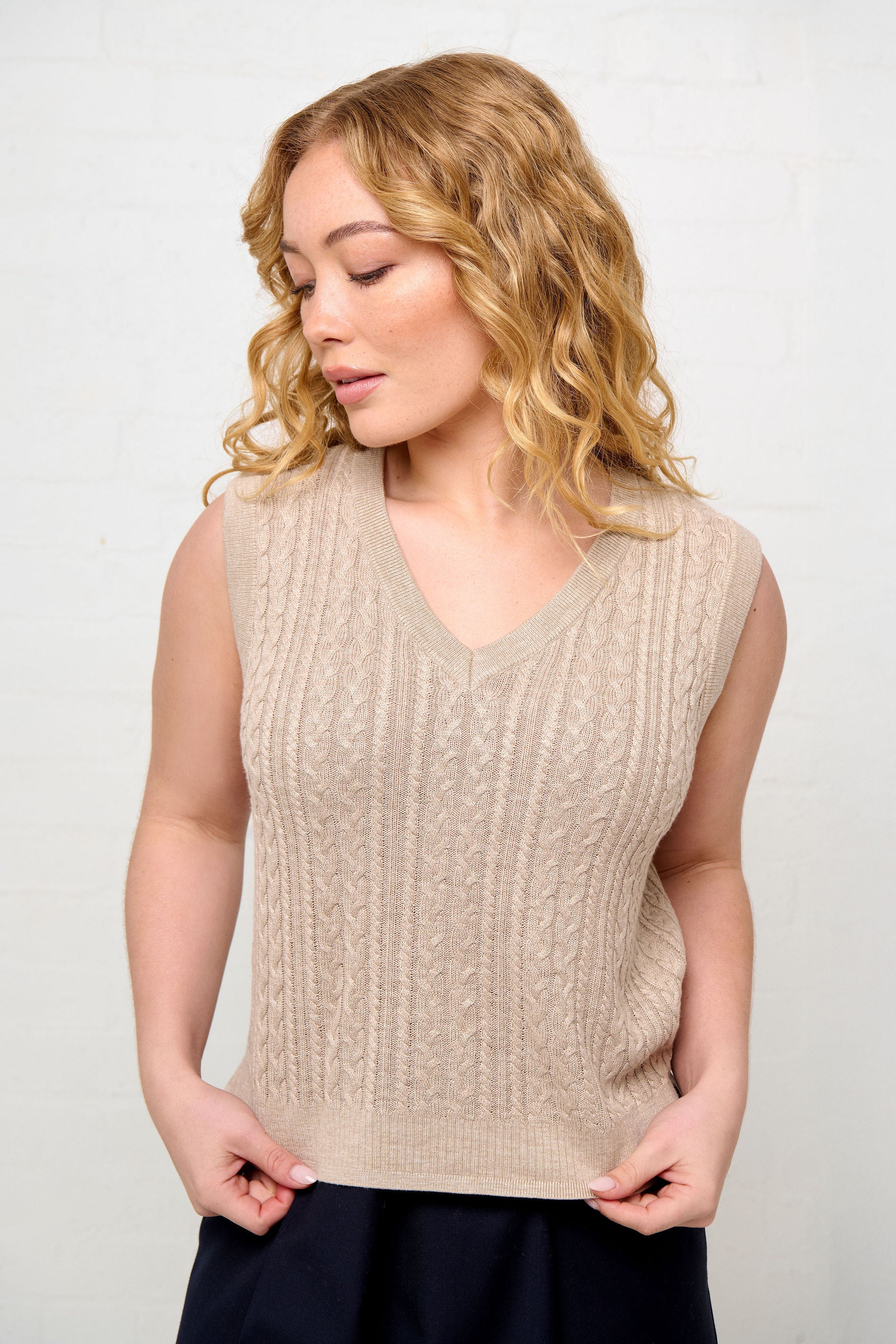 Woman wearing a beige sleeveless cable knit with a blend of silk and cotton. The vest is designed with the right size, shape, length and sleeveholes for the petite woman.